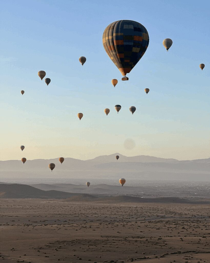 Multiple hot air balloons floating over Marrakech desert at sunrise