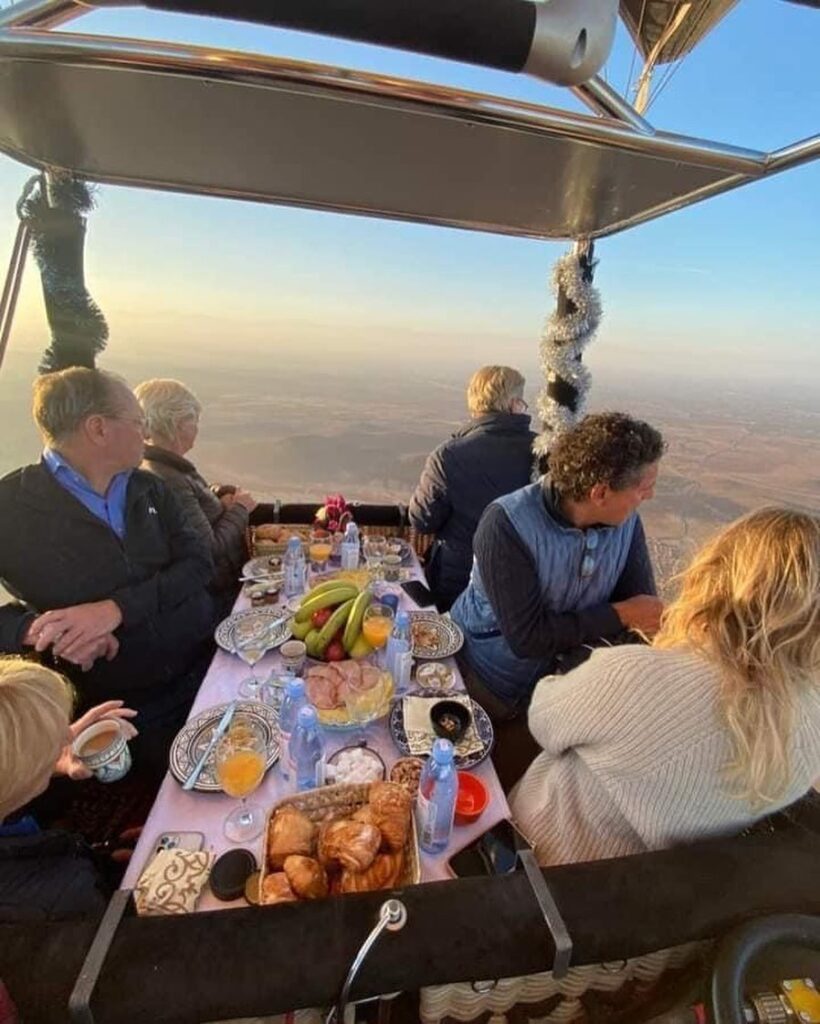 Passengers enjoying breakfast during hot air balloon flight in Marrakech