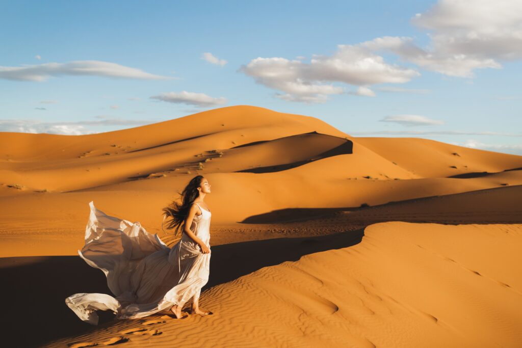Woman posing on sand dunes during Sahara Desert tour in Morocco
