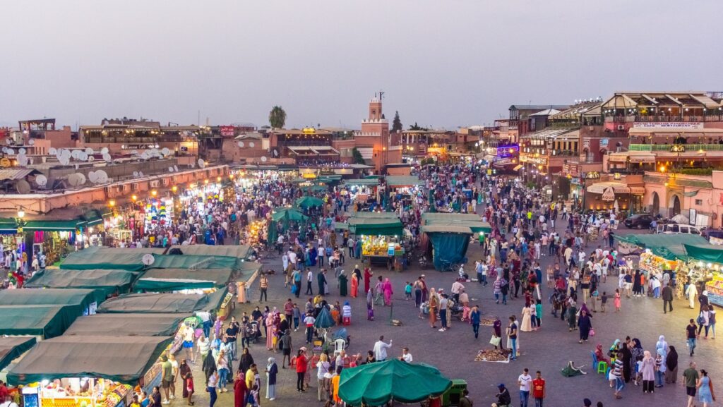 Crowded Jemaa el-Fna square in Marrakech at sunset filled with local markets, food stalls, and tourists