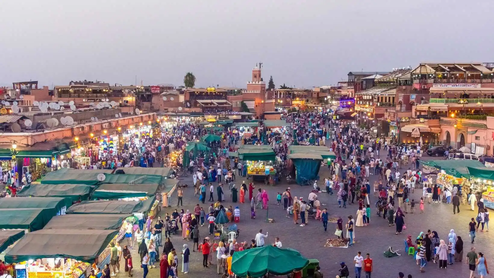 Crowded Jemaa el-Fna square in Marrakech at sunset filled with local markets, food stalls, and tourists