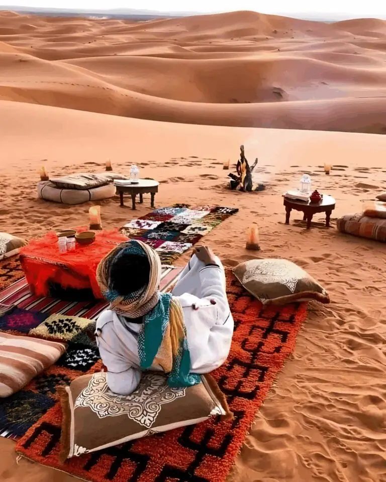 Rugs, cushions and lanterns set out on the dunes at a Merzouga desert camp