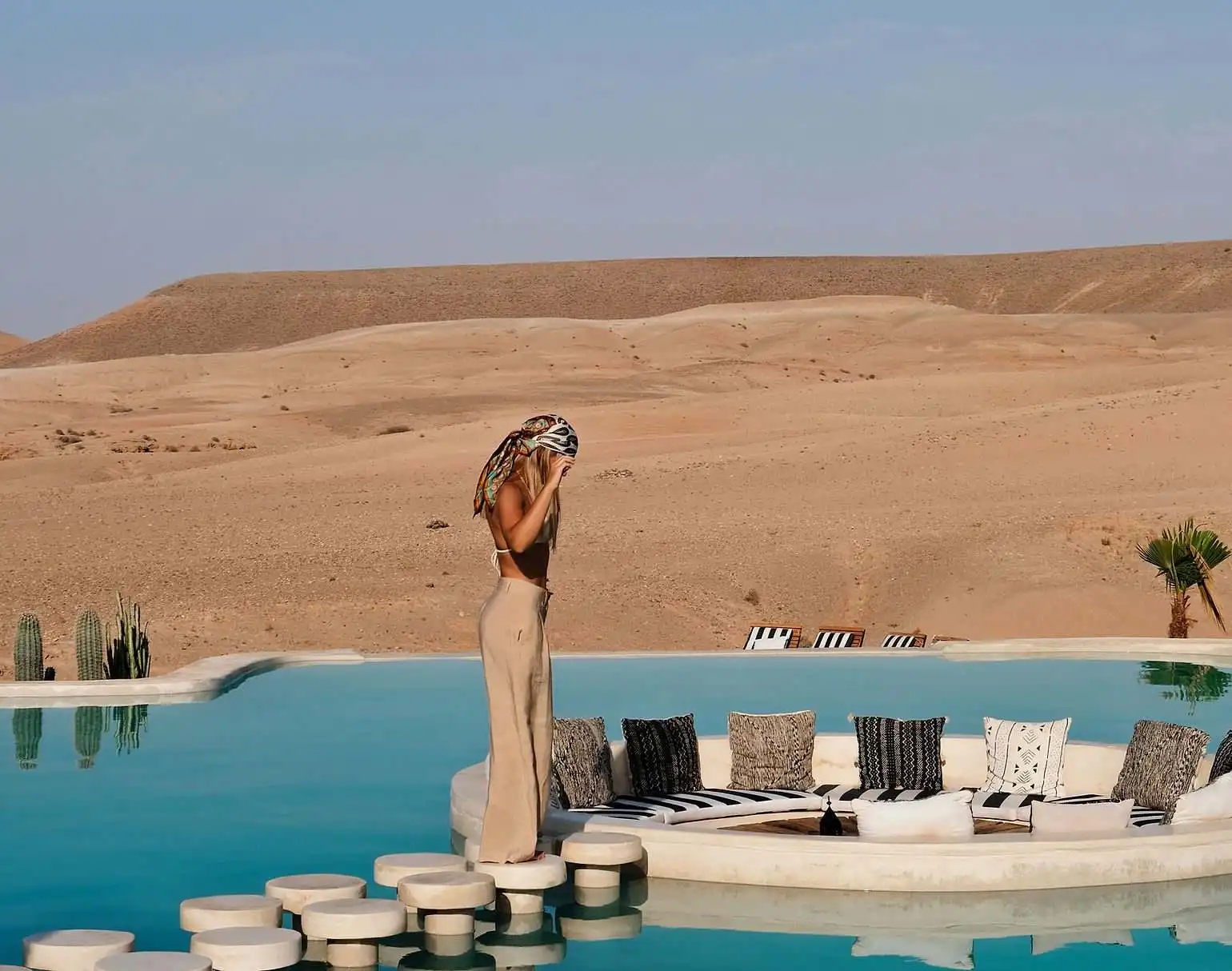 Traveller by a pool facing the stone hills of the Agafay Desert