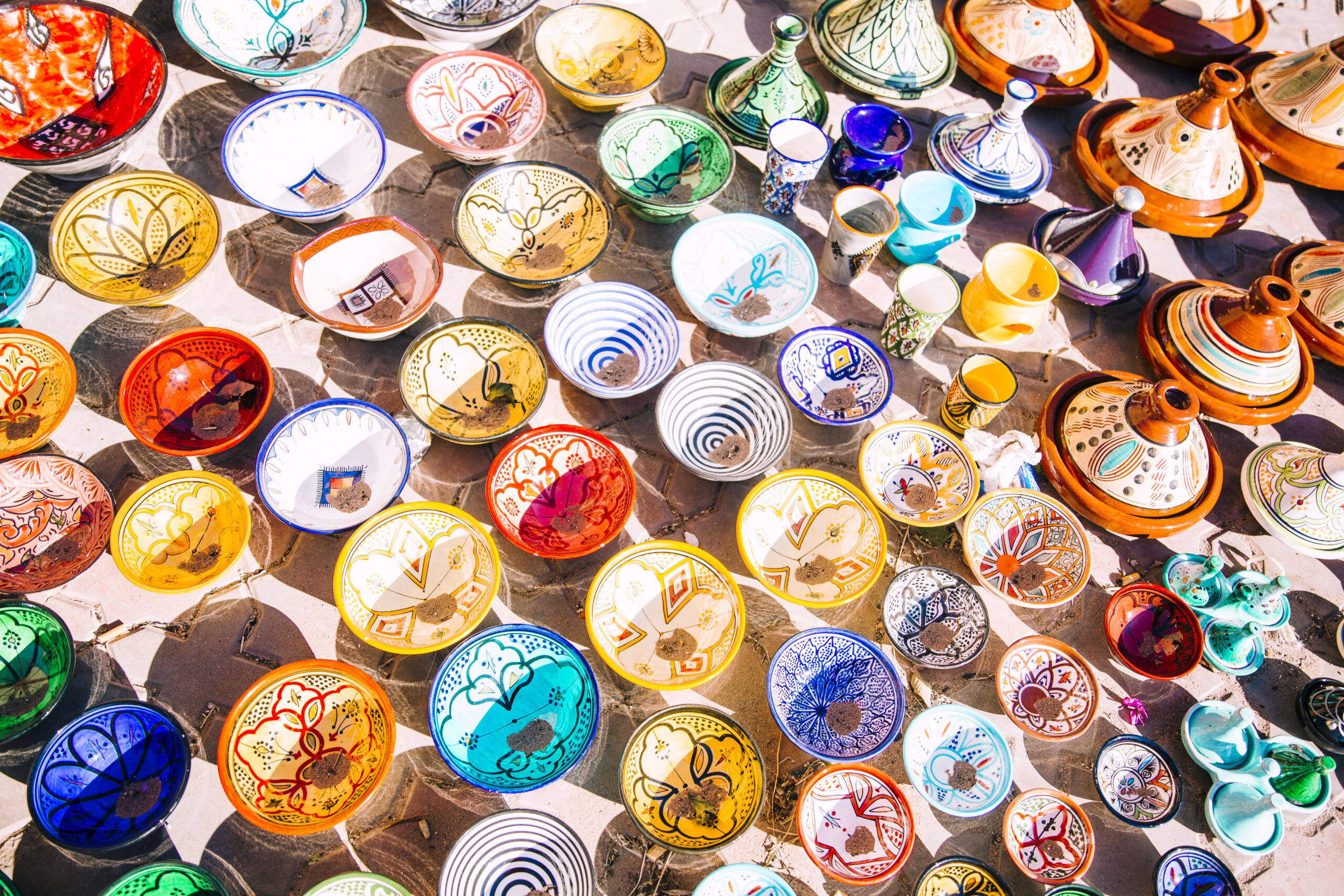 How Much Does a Trip to Morocco Cost? A Real 2026 Budget Breakdown 3 Stacks of colorful hand-painted Moroccan plates and bowls for sale at a market