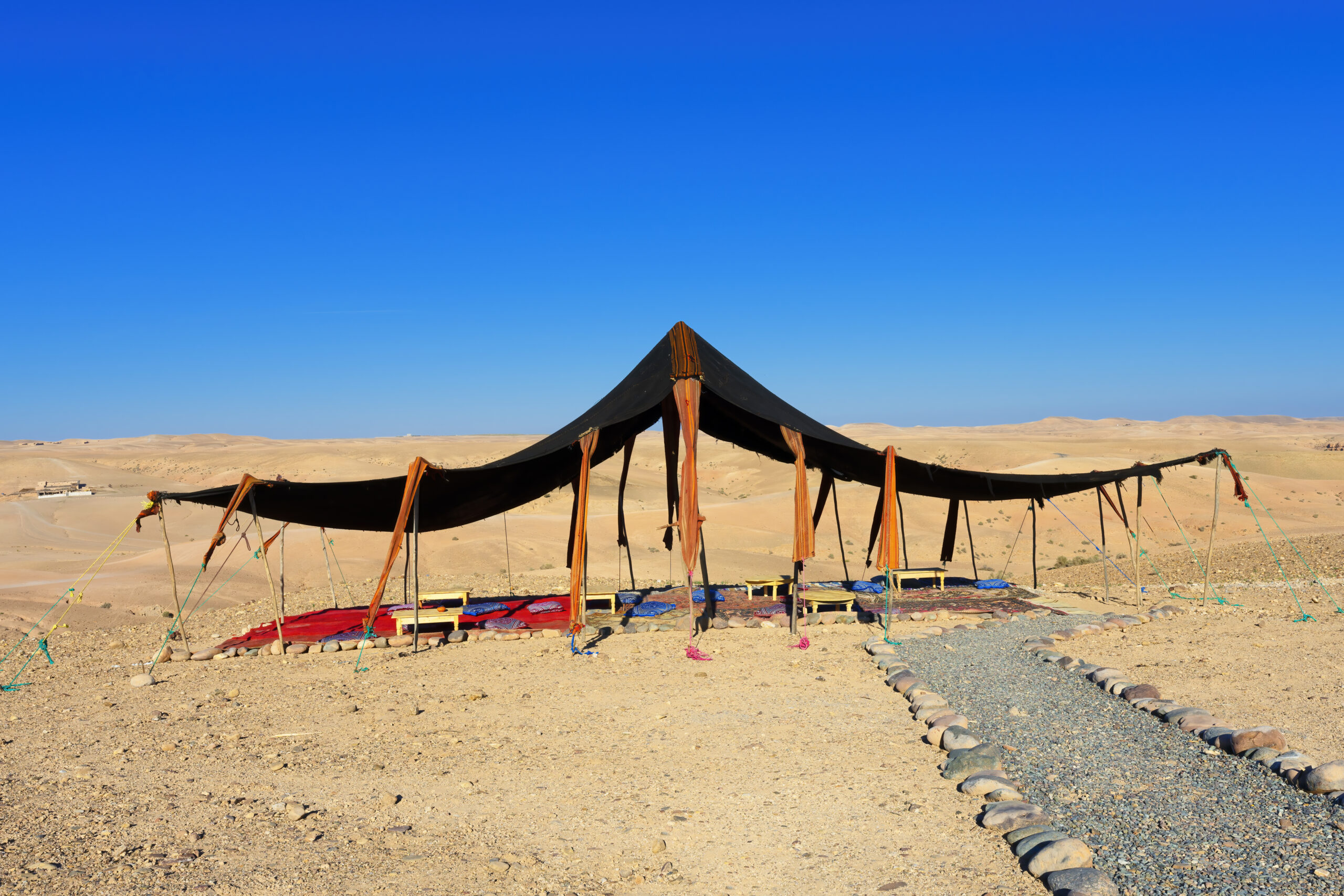 A Berber-style tent glowing at dusk in Morocco's Agafay Desert, set for a romantic overnight camp near Marrakech